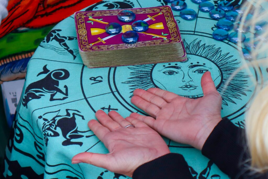 Hands hovering over a tarot deck and illuminated palms, cinematic lighting